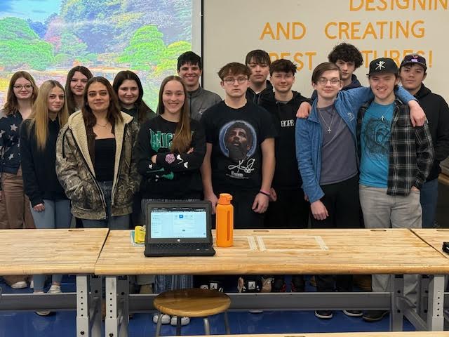 A group of students posing together, smiling at the camera. They are standing close, some with arms around each other, showing a sense of camaraderie and teamwork.