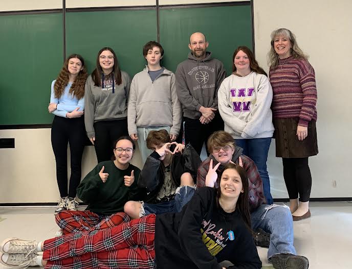 A group of students posing together, smiling at the camera. They are standing close, some with arms around each other, showing a sense of camaraderie and teamwork.