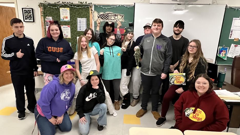 A group of students posing together, smiling at the camera. They are standing close, some with arms around each other, showing a sense of camaraderie and teamwork.