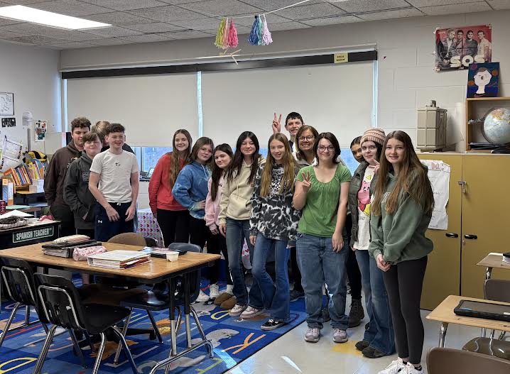 A group of students posing together, smiling at the camera. They are standing close, some with arms around each other, showing a sense of camaraderie and teamwork.