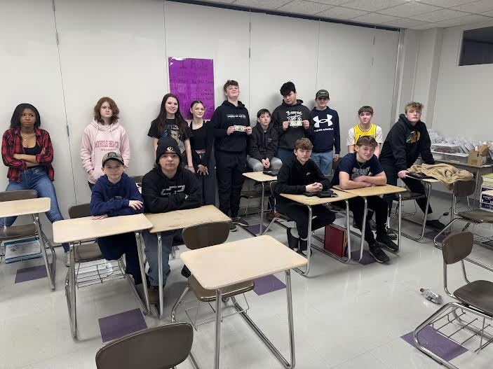 A group of students posing together, smiling at the camera. They are standing close, some with arms around each other, showing a sense of camaraderie and teamwork.
