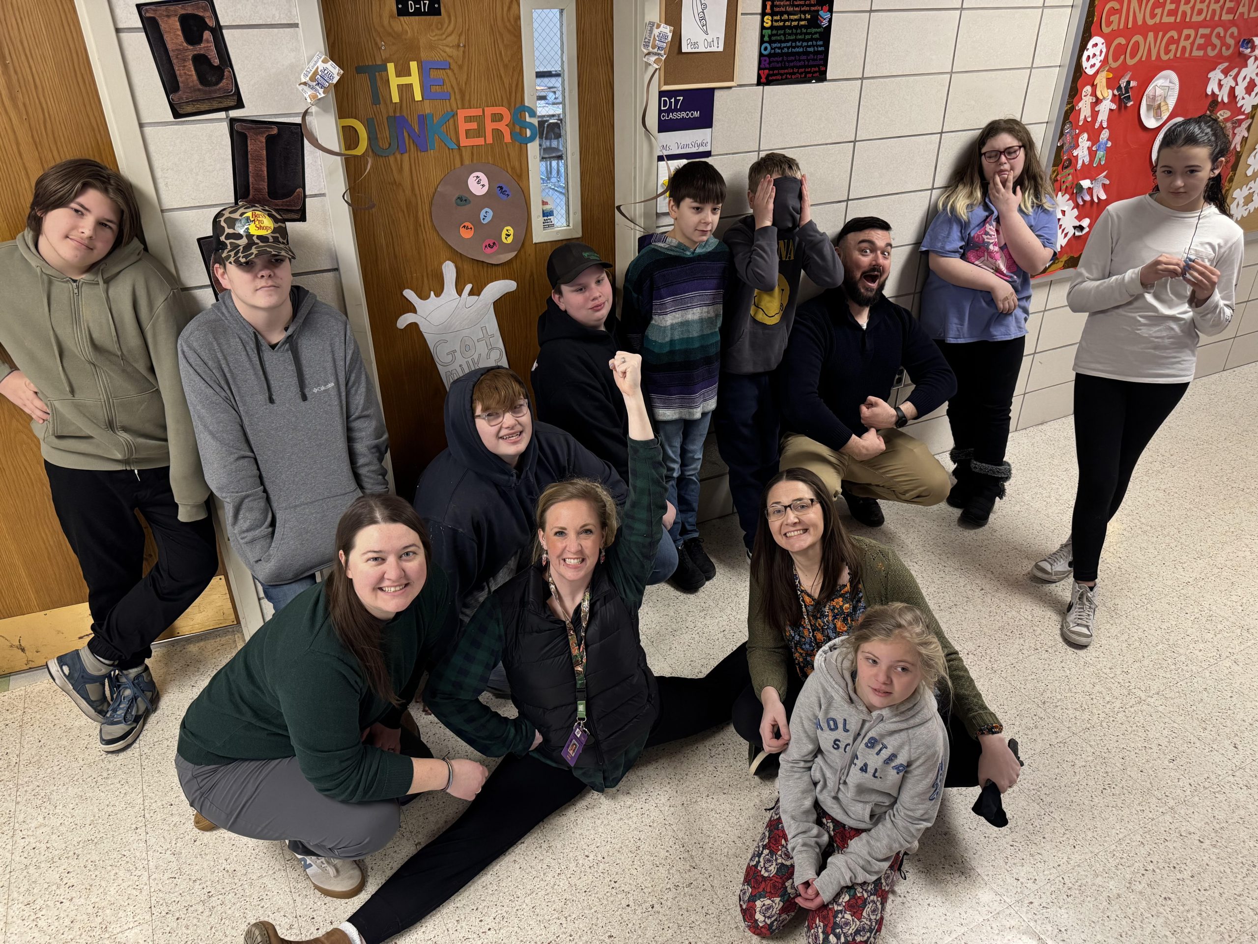 A group of students posing together, smiling at the camera. They are standing close, some with arms around each other, showing a sense of camaraderie and teamwork.