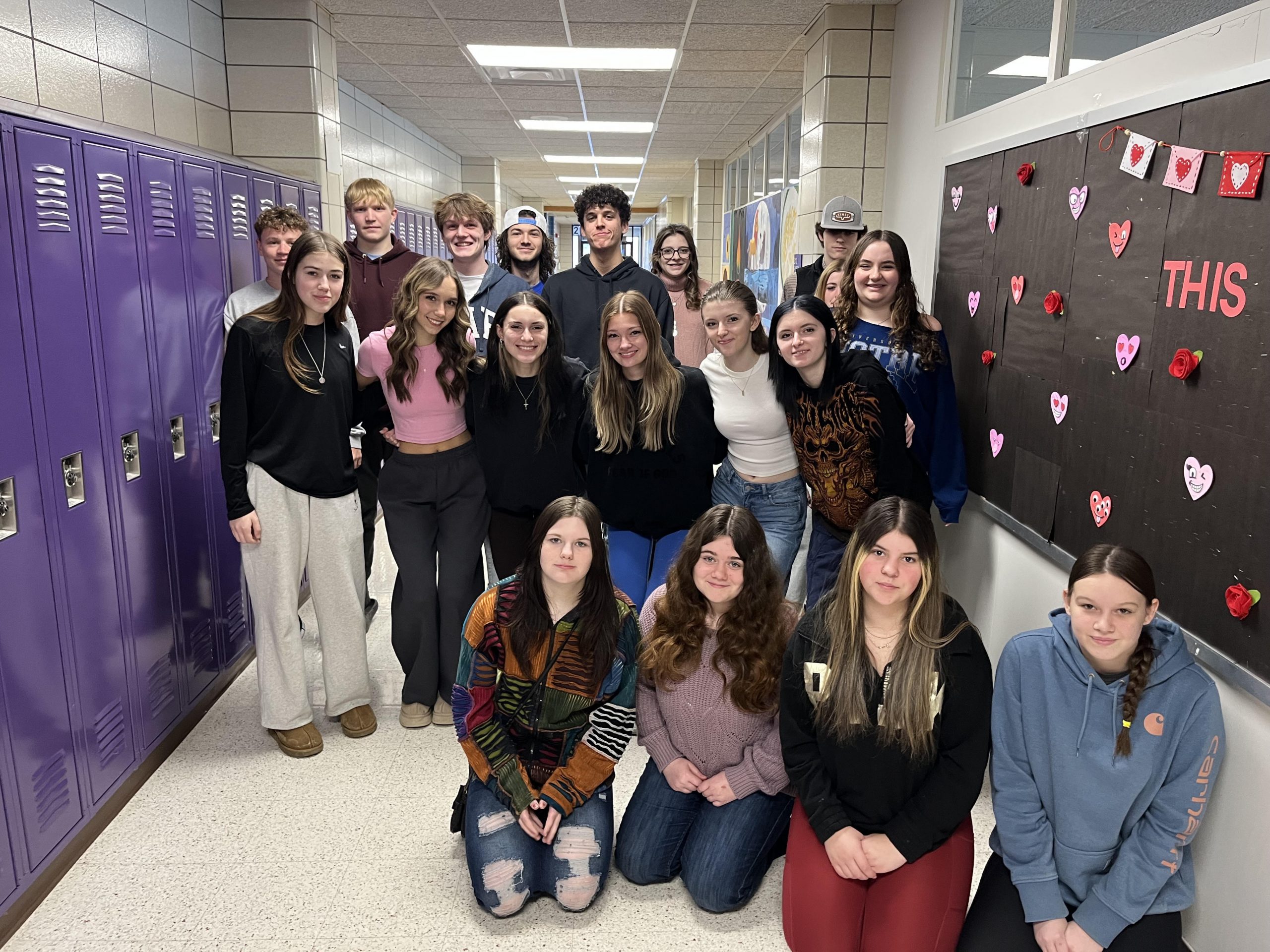 A group of students posing together, smiling at the camera. They are standing close, some with arms around each other, showing a sense of camaraderie and teamwork.