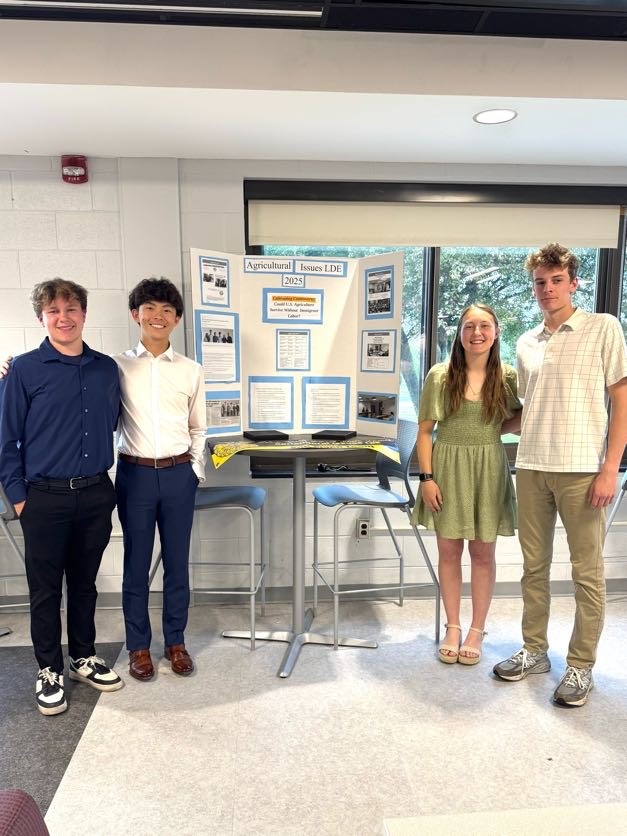 Photo of McKenna Furner, Nathan Jones, Cooper Patterson, Edmond Yang with poster Could U.S. Agriculture Survive Without Immigrant Labor?