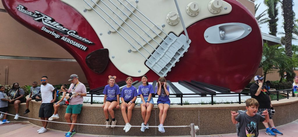 Photo of Waterville Central School marching band and swing choir students at Walt Disney World’s Epcot in front of a giant guitar