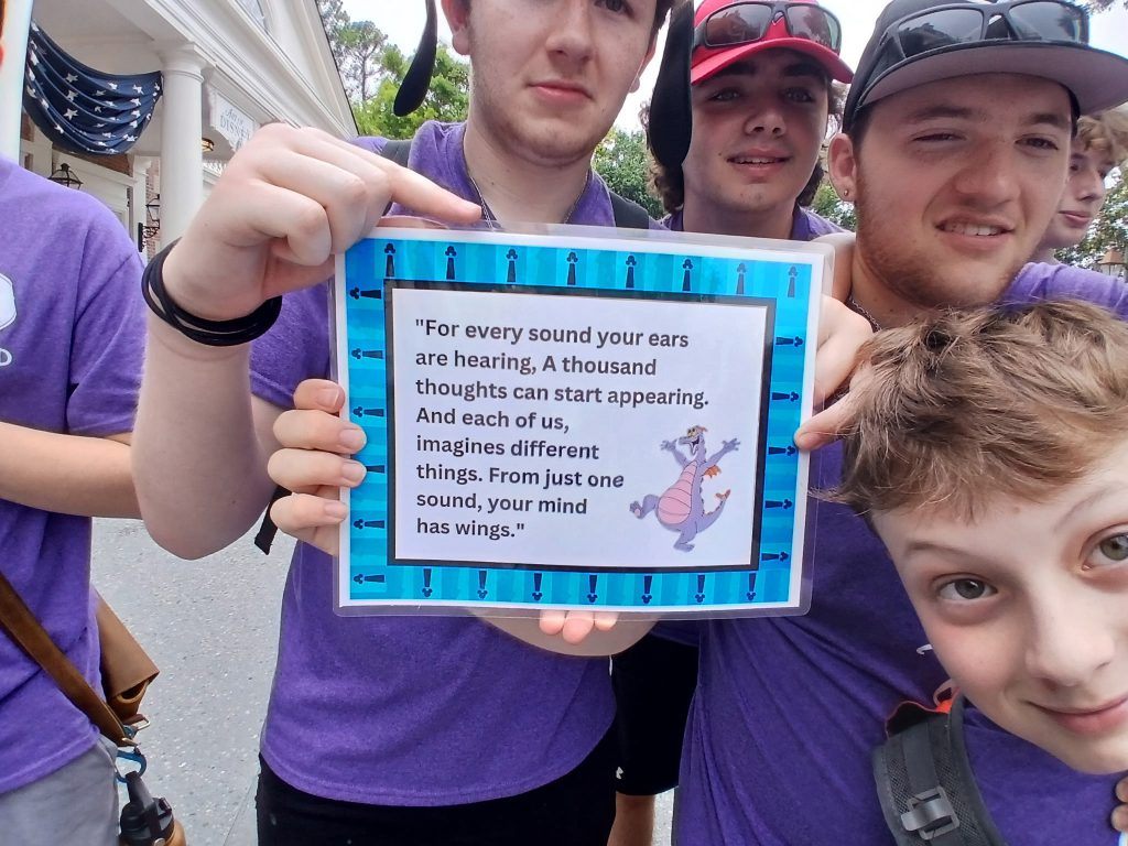 Photo of five students holding a sign that says "For every sound your ears are hearing, A thousand thoughts can start appearing. And each of us, imagines different things. From just one sound, your mind has wings."