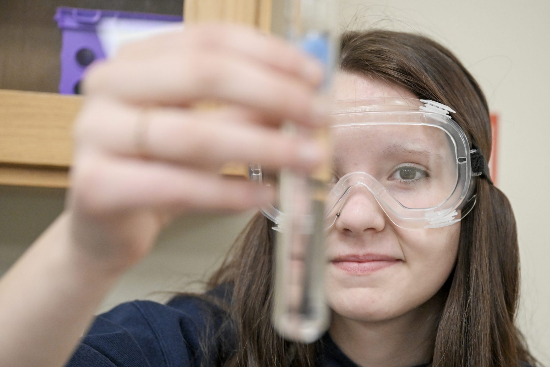 student holding a test tube and is wearing eye glasses