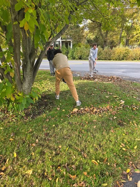 three students raking leaves
