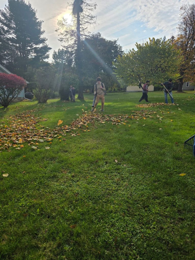 four students raking leaves