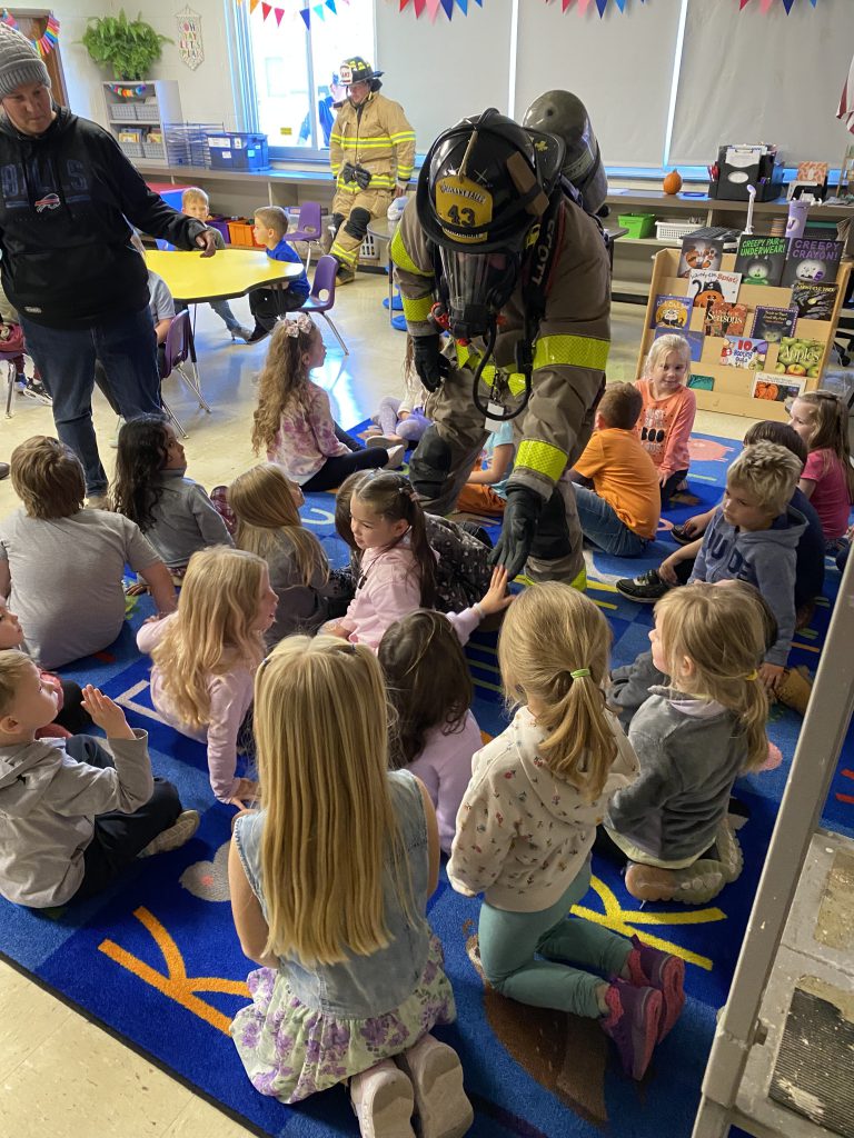 A firefighter high fives a student