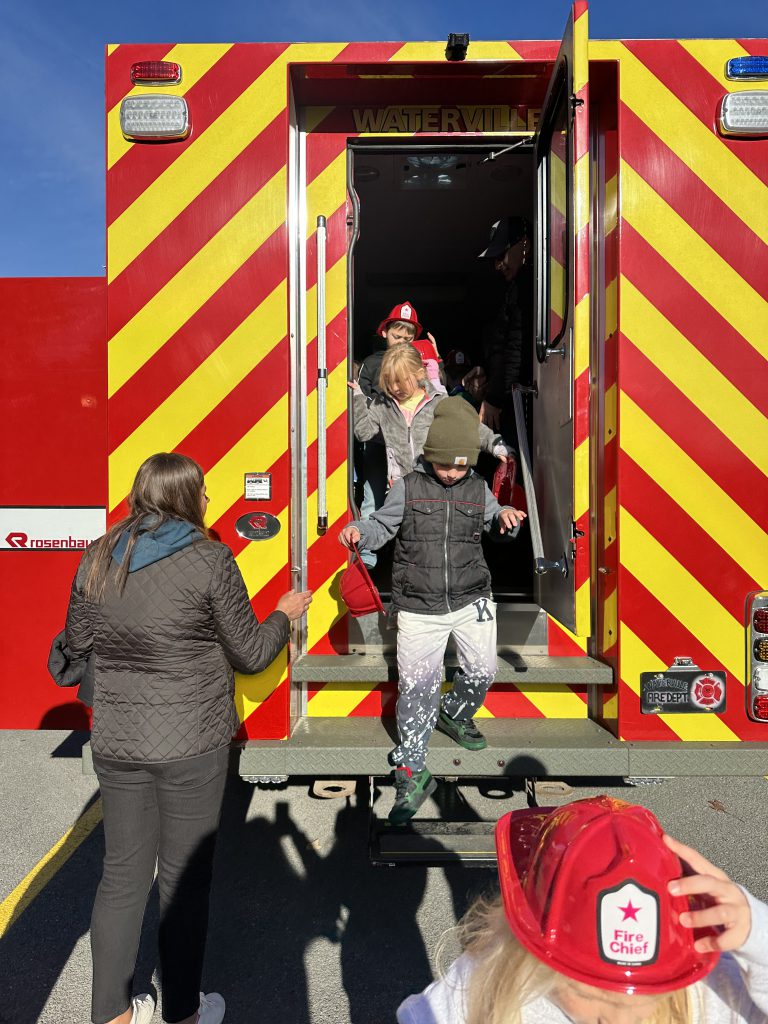 Three students exit firetruck walking down the stairs.